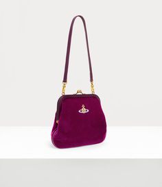 The Vivienne's clutch features a polished kiss-lock frame, reminiscent of early 20th-century antique coin purses, complete with antique gold plating. The piece receives a cotton velvet silhouette, complete with an embroidered orb on the front panel - embodying Vivienne's innovative vision of launching tradition into the future. Purple Vivienne Westwood, Velvet Purse, The Vivienne, Antique Coins, Into The Future, Socks And Tights, Knitwear Tops, Watch Gifts, Coin Purses