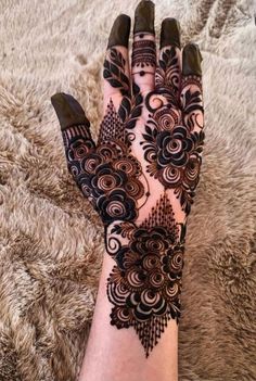 a woman's hand is decorated with hennap and black flowers on it