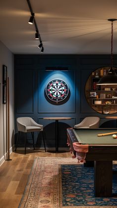 a game room with a pool table, chairs and darts on the wall behind it