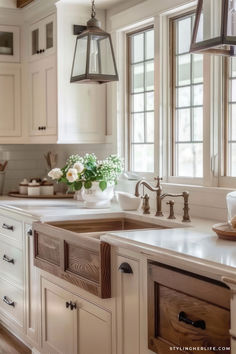 a kitchen with white cabinets and wooden floors, an island style sink and two hanging lights