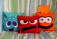 three pillows with different colored faces on them