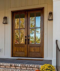 the front door to a home with two pumpkins on the steps