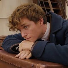 a young man leaning his head on top of a suitcase