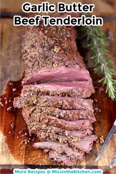 sliced meat sitting on top of a wooden cutting board next to a knife and sprig of rosemary