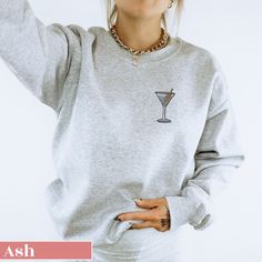 Elevate your casual wardrobe with our Embroidered Dirty Martini Sweatshirt! This cozy and stylish sweatshirt features a beautifully detailed martini glass with olive embroidery. Perfect for those who appreciate a touch of sophistication in their everyday wear, this sweatshirt combines comfort with a chic design. Made from high-quality fabric, it provides warmth and durability, making it an ideal addition to your closet. Whether you're lounging at home or stepping out for a casual outing, this em Casual Party Sweatshirt, Casual Long Sleeve Party Sweatshirt, Trendy Party Sweater With Crew Neck, Trendy Crew Neck Sweater For Party, Casual Crew Neck Sweater For Party, Casual Winter Party Sweatshirt, Olive Embroidery, Glass Embroidery, Gin Martini