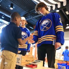 two young men standing next to each other in front of boxes with hockey jerseys on them