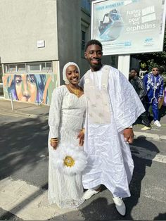 a man and woman dressed in white standing on the street