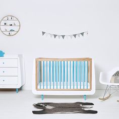 a baby crib in a white room with blue and white decor on the walls