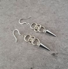 "Add some edgy urban style to your wardrobe with these hoop and spike drop earrings. 💀 DESCRIPTION: This pair of silver drop earrings were created with jump rings and spike charms. The earrings were attached to hypoallergenic stainless steel ear wires. 💀 SIZE & MATERIALS: The spikes measure approximately 7/8\" by 1/4\". They are made from a zinc alloy metal which is lead and nickel free. Overall, the earrings measure 2\" long and the drop is 1/2\". 💀 GIFT GIVING: These silver spike and lo Streetwear Dangle Pierced Earrings, Streetwear Dangle Earrings, Edgy Metal Dangle Hoop Earrings, Punk Style Metal Dangle Hoop Earrings, Single Metal Earring For Streetwear, Edgy Pierced Metal Earrings, Punk Dangle Earrings For Streetwear, Trendy Metal Earrings For Streetwear, Edgy Metal Earrings With Ear Wire