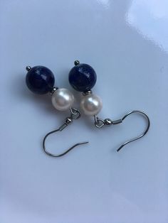 "Lapis lazuli gemstone earrings: A 10mm Lapis lazuli gemstone with 8mm ivory shell pearls, this earrings about 2\" long top to bottom, and it's made with stainless steel, Hypoallergenic. Hand made jewelry." Adjustable Blue Pearl Drop Jewelry, Elegant Blue Pearl Earrings With Natural Stones, Elegant Lapis Lazuli Earrings With Natural Stones, Nickel-free Blue Pearl Earrings Gift, Blue Sterling Silver Pearl Earrings As Gift, Blue Pearl Drop Jewelry For Gift, Silver Lapis Lazuli Round Earrings, Handmade Round Lapis Lazuli Earrings, Silver Round Lapis Lazuli Earrings