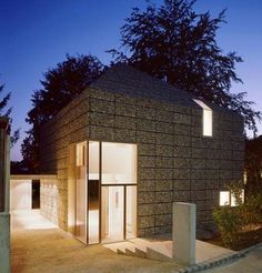 a house made out of bricks sitting on the side of a road at night time