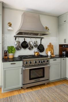 a stove top oven sitting inside of a kitchen next to a wall mounted pot rack