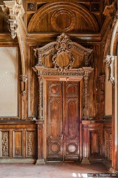 an ornate wooden door in the middle of a room with carved woodwork on the walls