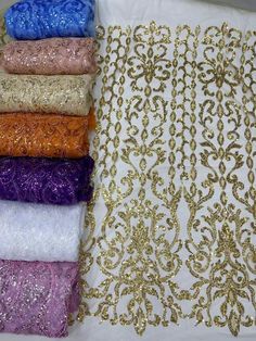 six different colors of sequins on a white table cloth with gold and silver designs