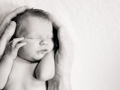 a man holding a baby in his arms and touching it's head with both hands