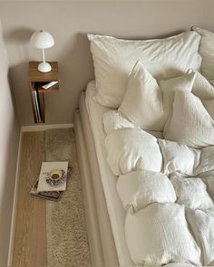 a bed with white pillows and a book on the floor