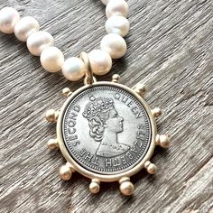 She's a stunner! Our Queen Elizabeth Necklace features hand knotted white freshwater pearls and a beautiful Queen Elizabeth reproduction coin pendant. Great gift idea for any fan of the Queen! Necklace is 18 inches in length and coin pendant is 40mm round.  Choose your pendant - shiny gold or matte gold. Pearls are authentic freshwater potato pearls and approximately 9-10mm in size. Clasp is gold (brass). I also carry freshwater pearl stud earrings which can be found here: https://www.etsy.com/l Coin Pearl Jewelry, Pearl And Coin Necklace, Pearl Chain Coin Necklace As Gift, Gold Pearl Jewelry With Coin Pendant, Pearl Necklace With Coin Pendant As Gift, Pearl Charm Coin Necklace Gift, Gift Pearl Chain Coin Necklace, Pearl Chain Coin Necklace Gift, Pearl Chain Coin Necklace