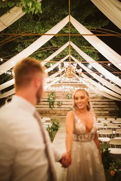 a bride and groom standing under a white tent