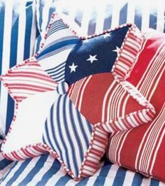 red, white and blue pillows on a couch with striped fabric in the background that has an american flag design