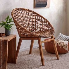 a wicker chair sitting next to a potted plant in a room with white walls