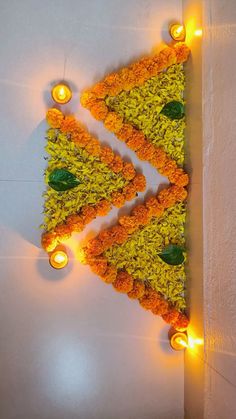 an arrangement of flowers and candles are arranged in the shape of a triangle on a wall