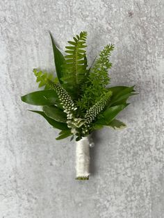 a white vase filled with green plants on top of a cement wall next to a planter