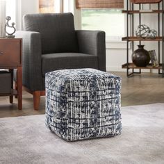 a blue and white ottoman sitting on top of a rug in front of a chair