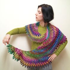 a woman wearing a colorful crochet shawl with her hands on her hips