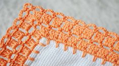 an orange and white crochet doily is laying on the tablecloths