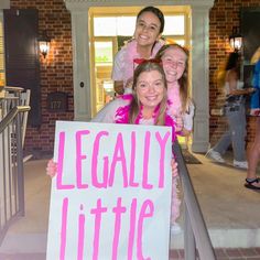 three girls holding up a sign that says legally little