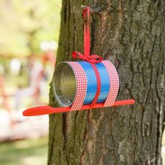 a red and blue ribbon hanging from a tree with a tin can attached to it