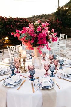 the table is set with plates, silverware and pink flowers