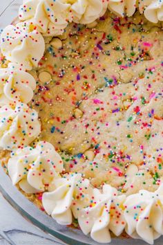 a cake with white frosting and sprinkles in a glass pie dish