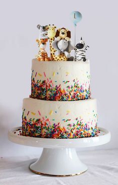 a three tiered cake with sprinkles and animals on top