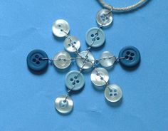 a snowflake made out of buttons on a blue tablecloth with a cord