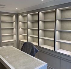 an empty room with white shelves and grey counter tops in front of the wall,