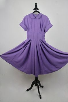 "1950s hand made dress. Purple rayon, plain weave fabric. The weight of the fabric would make a great swing dress. Peter Pan collar and cuffed cap sleeves. Wide, 3\" waist. Waist, collar, and cuffs have stiffening in them. Full skirt is box pleated and has reverse, decorative seaming. (see next to last photo although the color is off in this photo) 3.5\" hem. Fastens in the back with a short metal zipper and another one in the side. Freshly laundered. Excellent condition. There is one small dark Retro Solid A-line Vintage Dress, Solid Color A-line Retro Vintage Dress, Solid Color Retro A-line Vintage Dress, Fitted Dresses With Peter Pan Collar For Vintage Fashion, 1950s Style Lined Short Sleeve Dresses, 1950s Style Short Sleeve Lined Dress, Vintage Fashion Fitted Dress With Peter Pan Collar, Fitted Dress With Peter Pan Collar In Vintage Style, Classic Short Sleeve Lined Vintage Dress