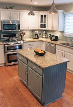 a large kitchen with an island in the middle and stainless steel appliances on both sides