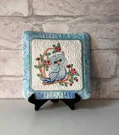 a small blue and white square with an owl on it's face sitting on a stand