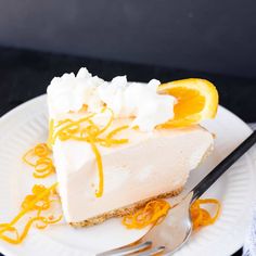 a slice of cheesecake on a white plate with orange zest and whipped cream