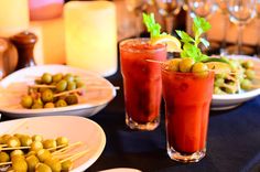 two glasses filled with olives on top of a table