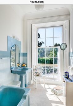 a blue bath tub sitting under a window next to a white sink and counter top