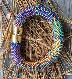 a colorful beaded bracelet sitting on top of dry grass next to a metal object