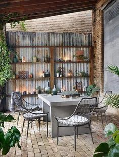 an outdoor dining area with brick walls and potted plants on the shelves above it