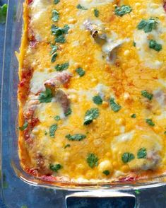 a casserole dish with cheese, meat and vegetables in it on a blue surface