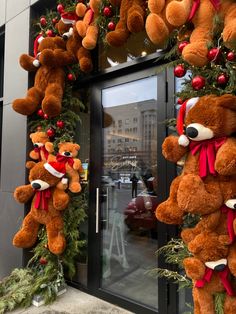 two teddy bears hanging from the side of a building decorated with christmas wreaths and decorations