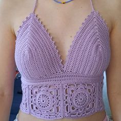 a woman wearing a purple crochet top with a blue necklace on her neck