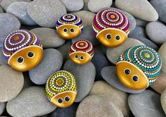 five colorful rocks sitting on top of each other next to some rocks and stones with eyes painted on them