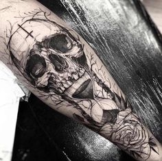 a black and white photo of a skull with roses on it's arm,