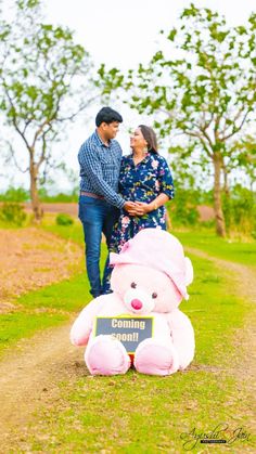 a man and woman standing next to a pink teddy bear